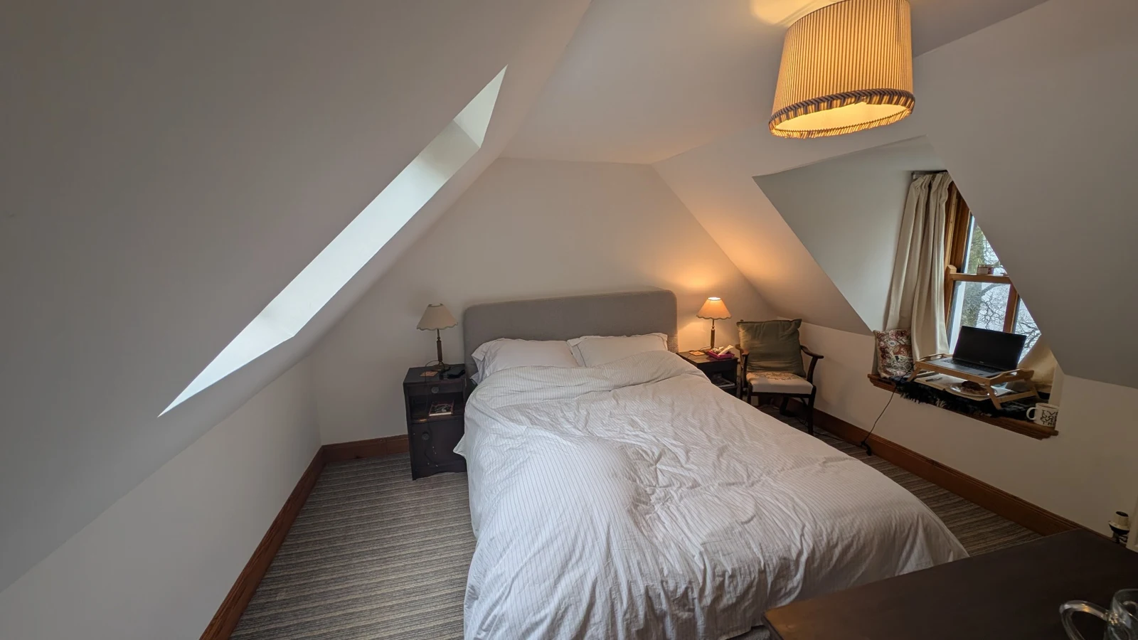 Upstairs bedroom with a made bed beneath the sloping ceiling