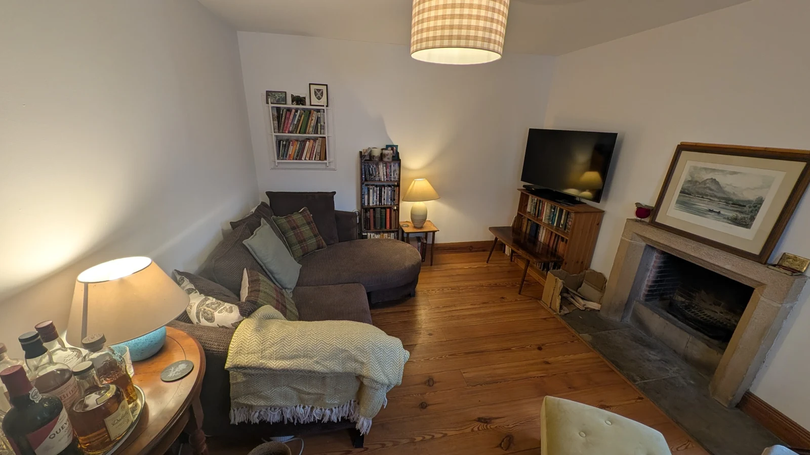 Living room with sofas, books, wooden floor and an open fireplace