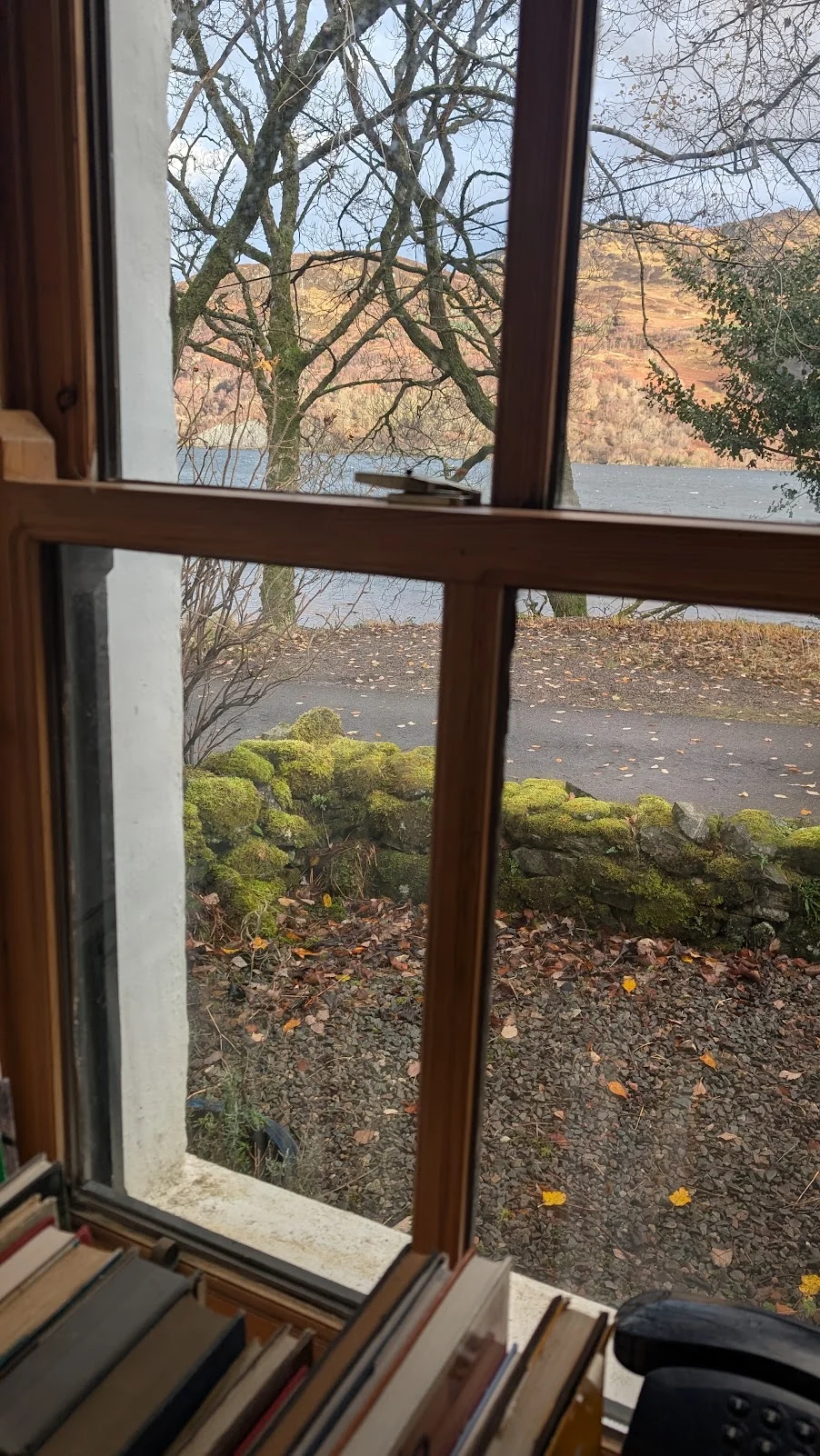Books by a cottage window looking towards the loch